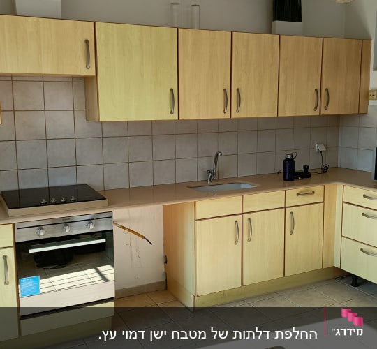 מטבח עם ארונות עץ, תנור, כיור ומקרר אפור